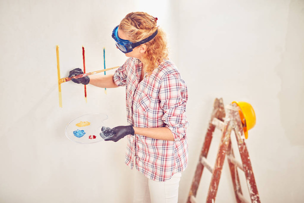 Arbeitende Frau verputzt / streicht Wände im Haus. - Foto, Bild