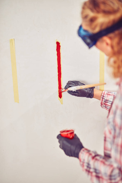 Εργασία γυναίκα πλεκτής/ζωγραφική τοίχους μέσα στο σπίτι. - Φωτογραφία, εικόνα