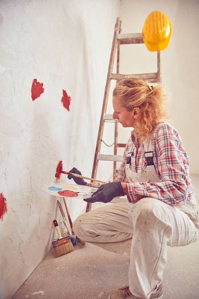 Robocza kobieta tynkowanie/malowanie ścian wewnątrz domu. - Zdjęcie, obraz
