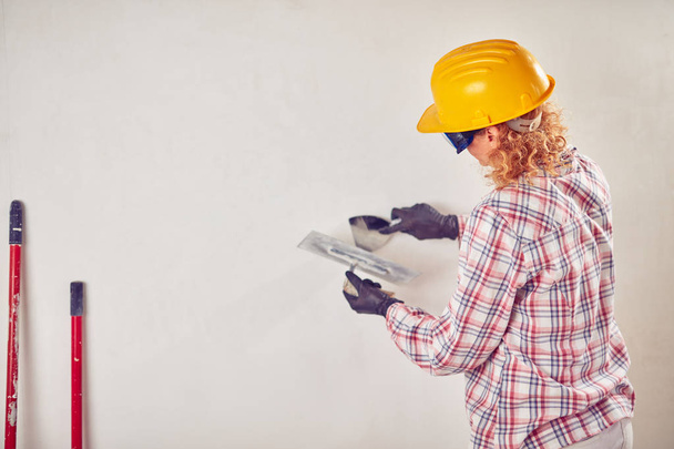 Working woman plastering / painting walls inside the house. - Foto, Bild