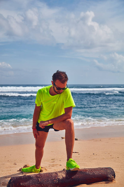 Sportivo che si estende su una spiaggia di sabbia tropicale
. - Foto, immagini