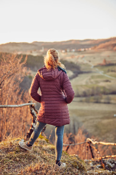 Woman looking at the distant hilly landscape. - Foto, afbeelding
