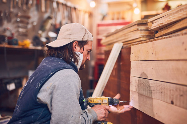 Carpintero macho trabajando en madera vieja en un taller retro vintage. - Foto, imagen