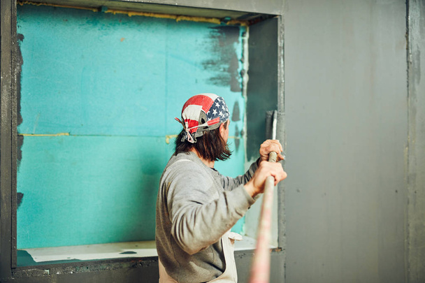 Pintor pintando paredes con un rodillo extensor en interiores
. - Foto, imagen