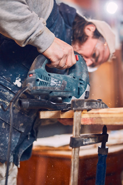 Mannelijke timmerman werkt aan oud hout in een retro vintage werkplaats. - Foto, afbeelding