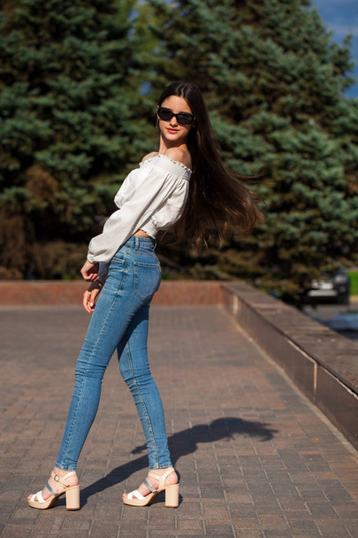 Pretty stylish brunette girl in blue jeans and white blouse  - Photo, image