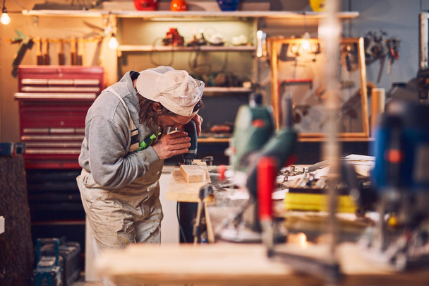 Αρσενικό ξυλουργός που εργάζονται σε παλιό ξύλο σε ένα ρετρό vintage εργαστήριο. - Φωτογραφία, εικόνα