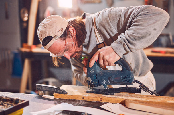 mężczyzna stolarz praca na stary drewno w retro vintage warsztat. - Zdjęcie, obraz