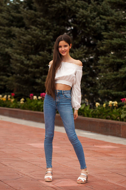 Pretty stylish brunette girl in blue jeans and white blouse  - Fotografie, Obrázek