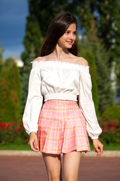 Pretty stylish brunette girl in plaid skirt and white blouse  - Fotoğraf, Görsel