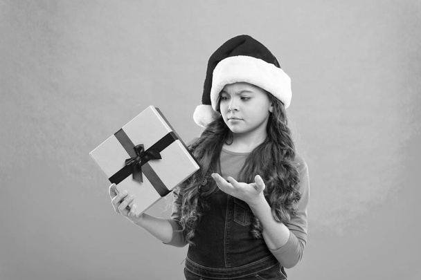 Present for Xmas. Childhood. New year party. Santa claus kid. Christmas shopping. Happy winter holidays. Small sad girl. Little girl child in santa hat. Wishing a happy New Year. waht is that - Foto, Bild