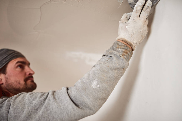 Trabalhador rebocando paredes de gesso dentro da casa
. - Foto, Imagem
