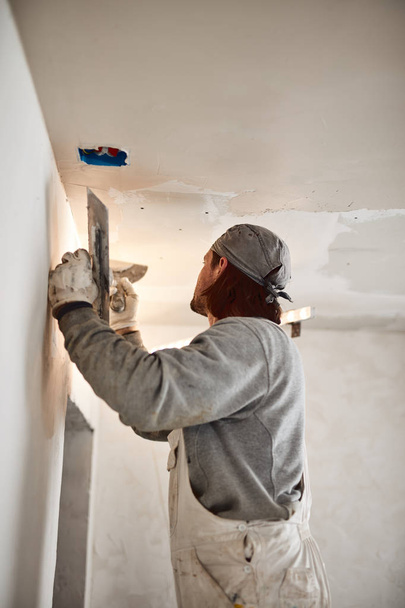 Trabajador enyesando paredes de yeso dentro de la casa
. - Foto, imagen