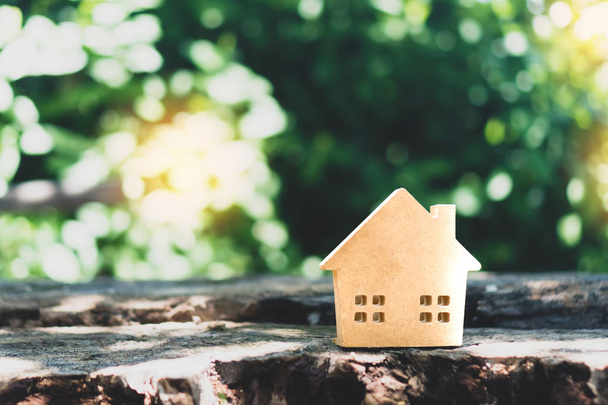 Gesloten klein huis model op vloer of houten bord met zonlicht groen bokeh achtergrond. Woning voor woon-of investerings concept. - Foto, afbeelding