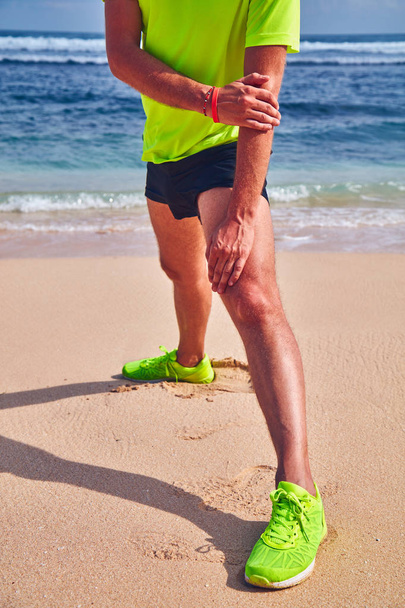 Sportsman stretching on a tropical sandy beach. - Valokuva, kuva