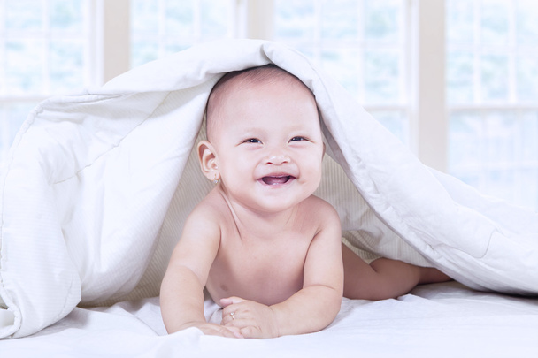 Baby laughing under blanket at home - Foto, afbeelding
