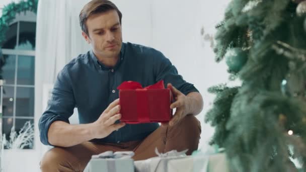 Smiling husband making surprise on christmas eve in living room - Imágenes, Vídeo