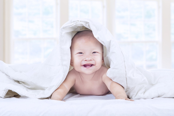 Cute baby laughing under blanket at home - Fotó, kép