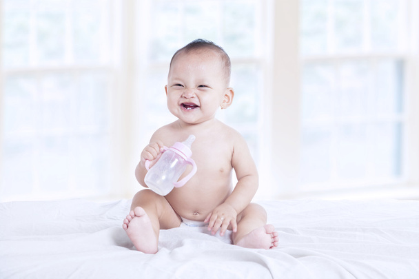 Happy baby with milk bottle indoor - Zdjęcie, obraz