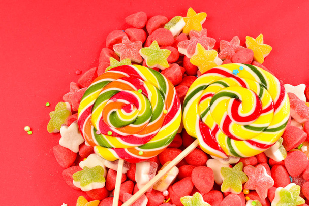 Çeşitli renkli sakızlı şekerler ve kırmızı arka plan üzerinde lolipop.  - Fotoğraf, Görsel