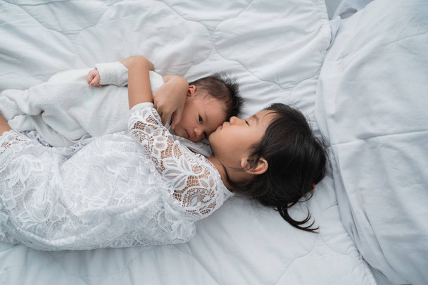 白い服を着てベッドで遊んで幼児の兄弟と娘の子供 - 写真・画像