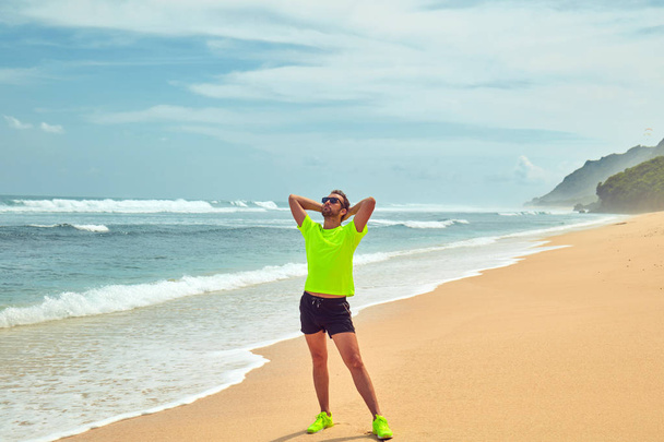Спортсмен тягнеться на тропічному піщаному пляжі
. - Фото, зображення
