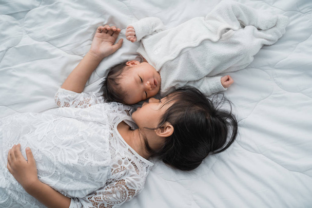 dochter Kid met zuigeling sibling spelen op bed dragen van wit - Foto, afbeelding