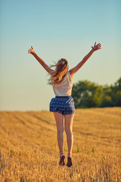 Mulher jovem bonito pulando em um campo de trigo
. - Foto, Imagem