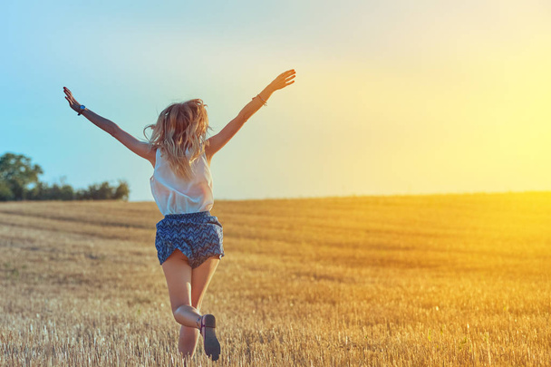 Cute young woman jumping in a wheat field. - Foto, Bild