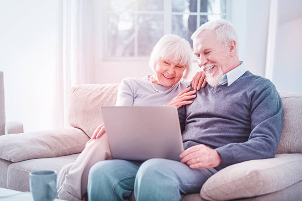 Муж и жена на пенсии смеются над комедией на ноутбуке
 - Фото, изображение