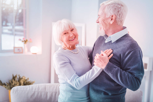 Beaming elderly lady feeling amazing while dancing with her husband - Foto, Bild