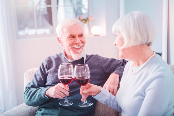 Couple of beaming pensioners clanging their glasses having romantic dinner - Fotó, kép