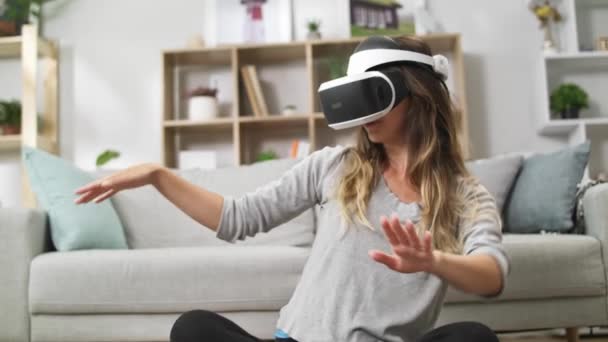 Young girl dancing sitting on the floor wearing virtual reality headset - Felvétel, videó