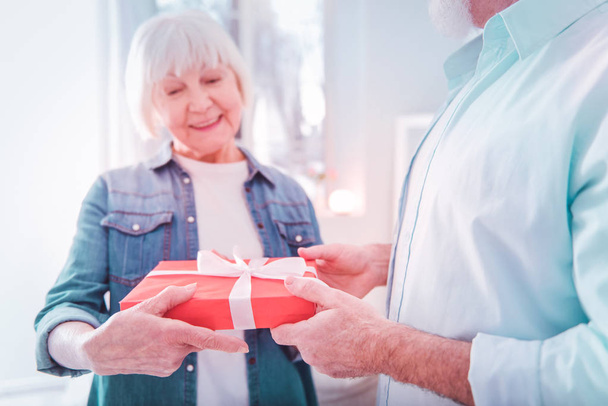 Beaming elderly lady wearing denim shirt receiving present box - Photo, image