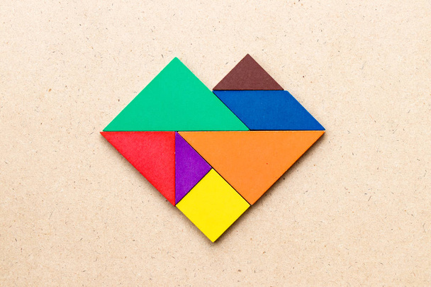 Color tangram puzzle in heart shape on wood background - Photo, Image