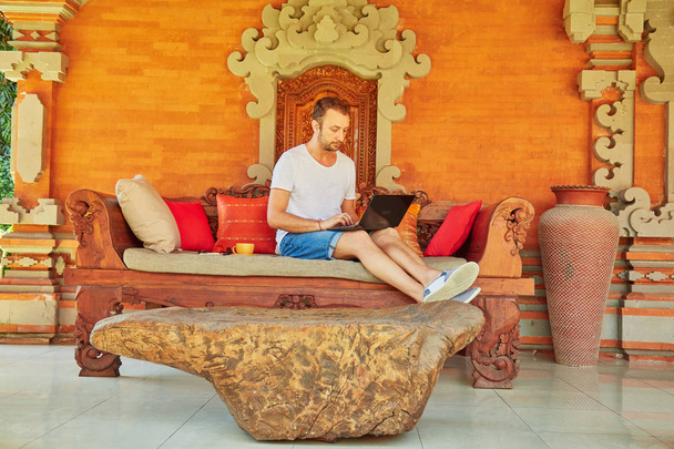 Homem com café / chá e laptop em um alpendre
. - Foto, Imagem