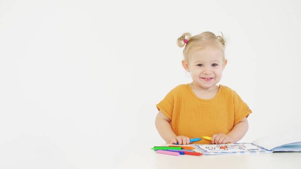 Smiling baby holds color crayons against white background - Фото, изображение