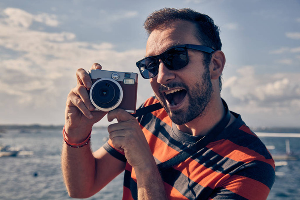 Człowiek za pomocą rocznika film kamery na Oceanie/wakacje nad morzem. - Zdjęcie, obraz