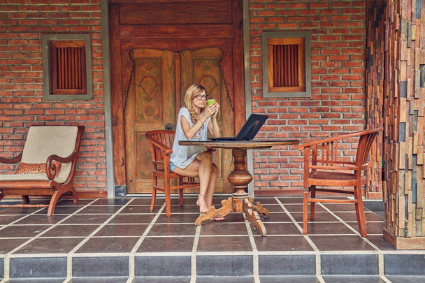 Freelancer meisje met smartphone, koffie/thee en laptop op een Ho - Foto, afbeelding