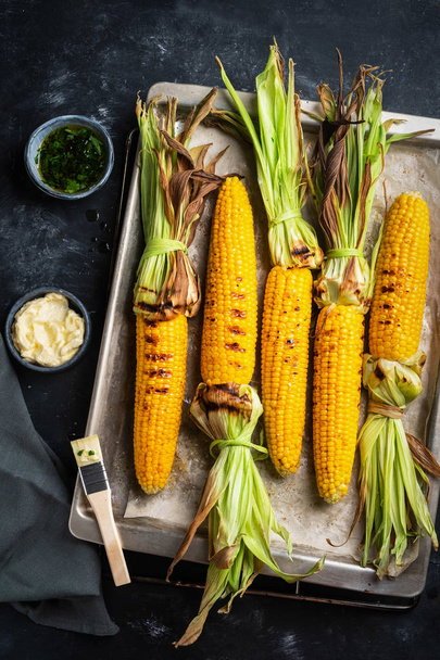 grilled corn on a baking sheet, top view, dark background, rustic style - Foto, Imagem