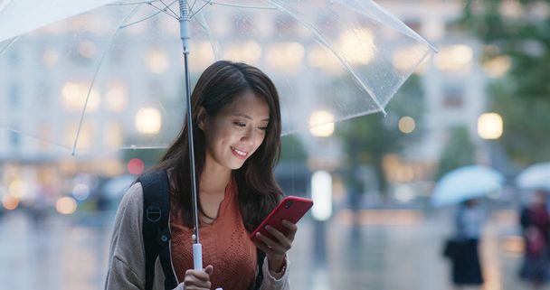 Woman hold with umbrella and use of mobile phone in the city at  - Foto, Imagen