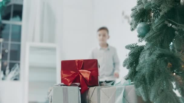 Κοντινά πλάνα νέος τύπος παίρνοντας δώρο κοντά σε χριστουγεννιάτικο δέντρο στο πολυτελές σπίτι. - Πλάνα, βίντεο