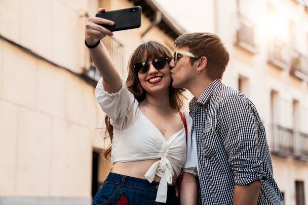 Uomo baciare donna sorridente prendendo selfie sulla strada
 - Foto, immagini