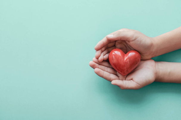 hands holding red heart on blue background, health care, love, o - Fotó, kép