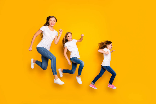 Full body photo of three ladies jumping high hurrying sale shopping wear casual clothes isolated yellow background - Foto, imagen
