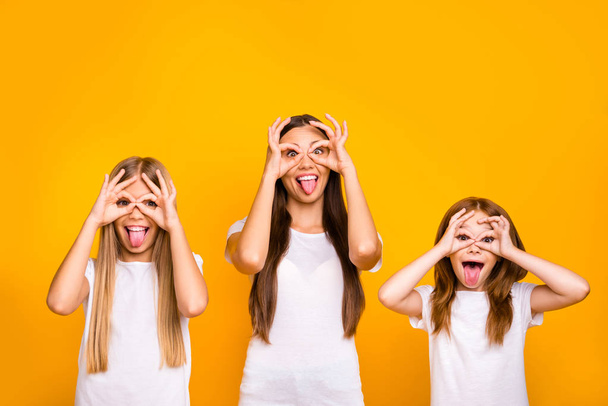 Three sister ladies holding okey symbols near eyes like specs fooling around wear casual outfit isolated yellow background - Photo, image