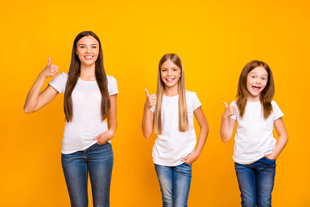 Pretty three sister ladies giving approval to tested product raising thumbs up wear casual outfit isolated yellow background - Фото, зображення
