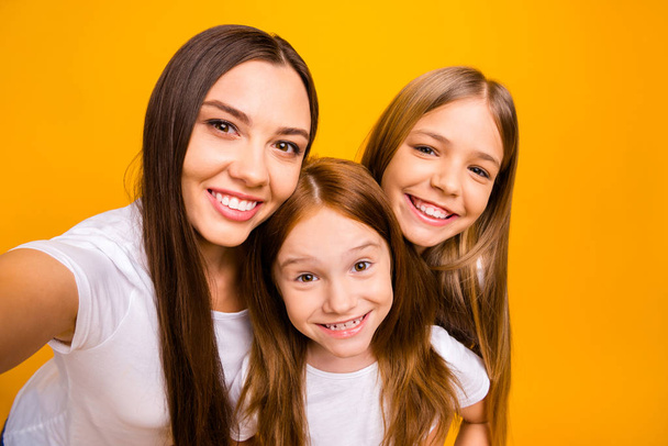 Photo of three sister ladies making funny selfies wear casual white t-shirts isolated yellow background - Foto, imagen