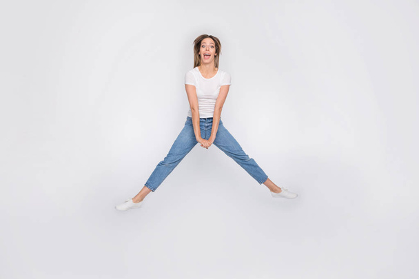 Full length body size photo of crazy funny cute nice attractive girl jumping trying to do splits while isolated with white background - Фото, изображение