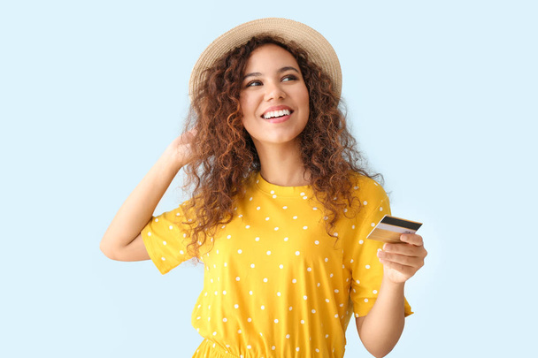 Mulher afro-americana feliz com cartão de crédito em fundo de cor clara
 - Foto, Imagem